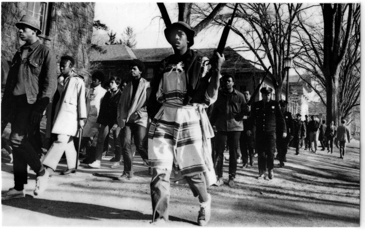 A man in native american garb holding two guns.