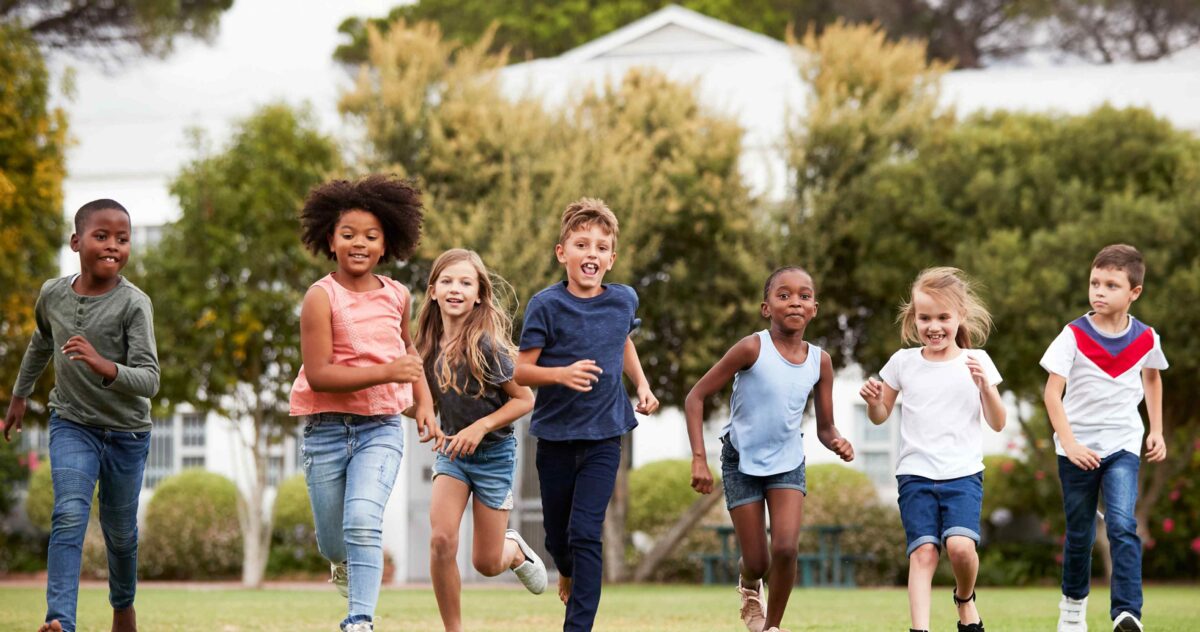 A group of children running in the grass.