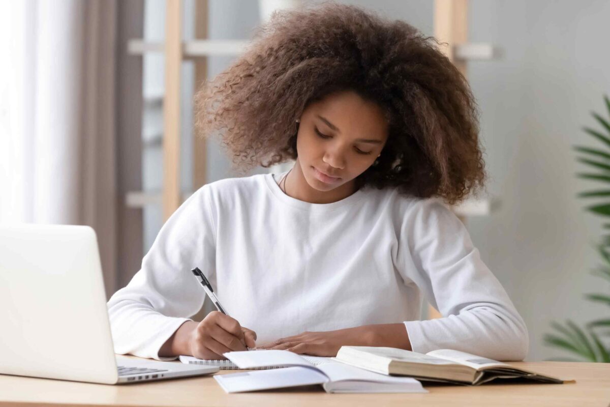 A woman sitting at a table writing on paper.