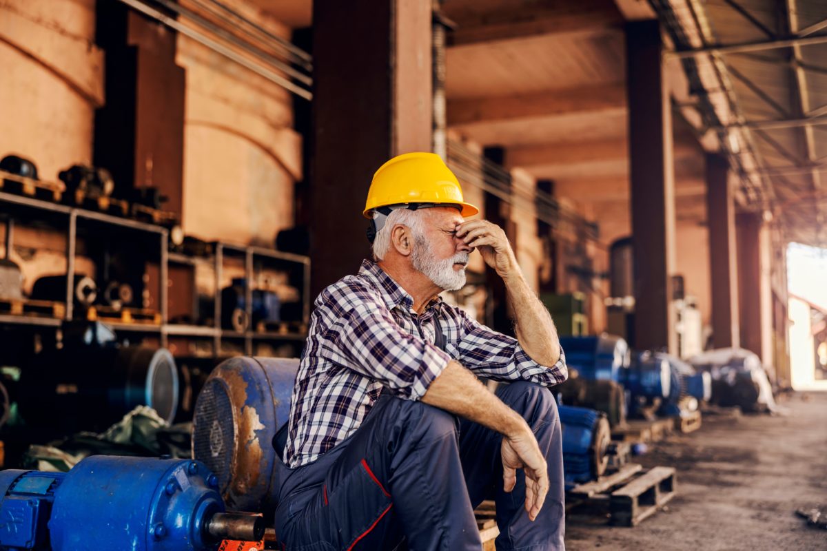 A man sitting on the ground wearing a hard hat.