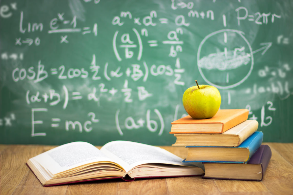 A green apple sitting on top of some books.